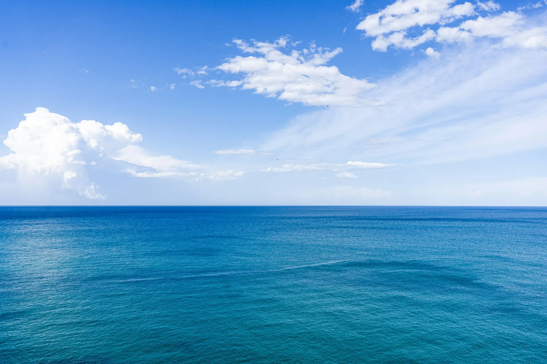 Open sea meeting a blue sky with white clouds